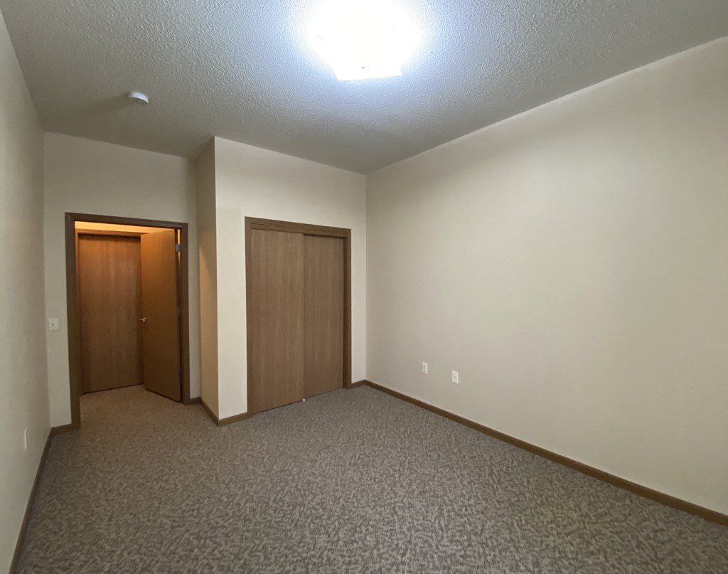 the living room of an empty apartment with a door to the hallway