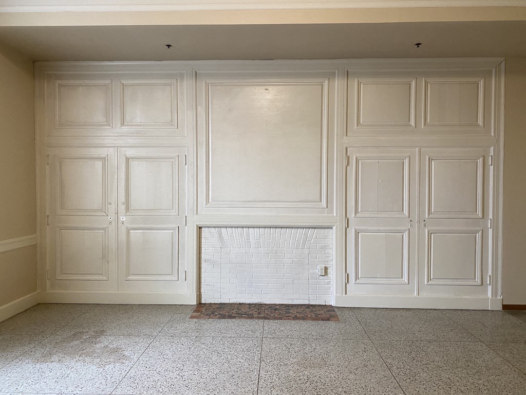 an empty room with white walls and a fireplace