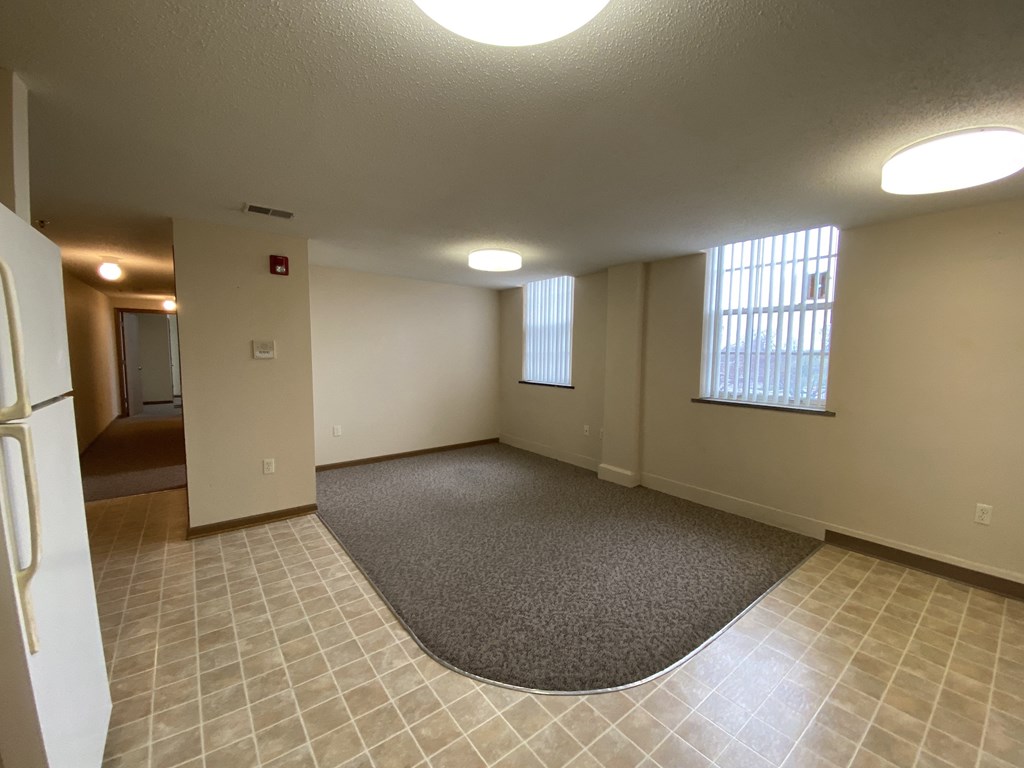 an empty living room with a rug and a window