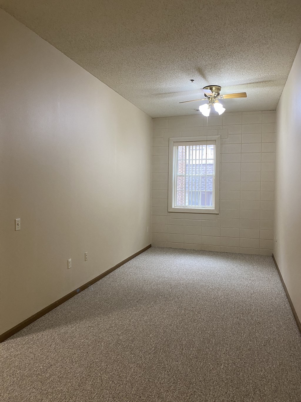 an empty room with a ceiling fan and a window