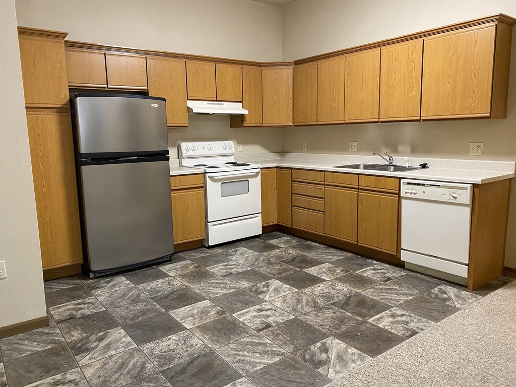 an empty kitchen with white appliances and wooden cabinets