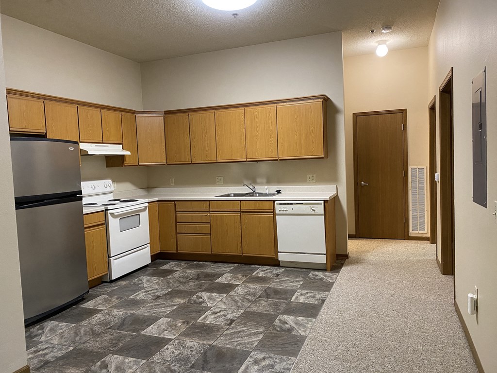an empty kitchen with white appliances and wooden cabinets