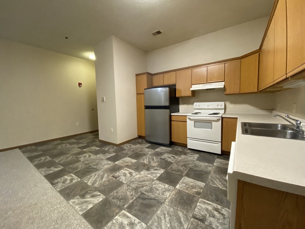 an empty kitchen with a stove refrigerator and sink