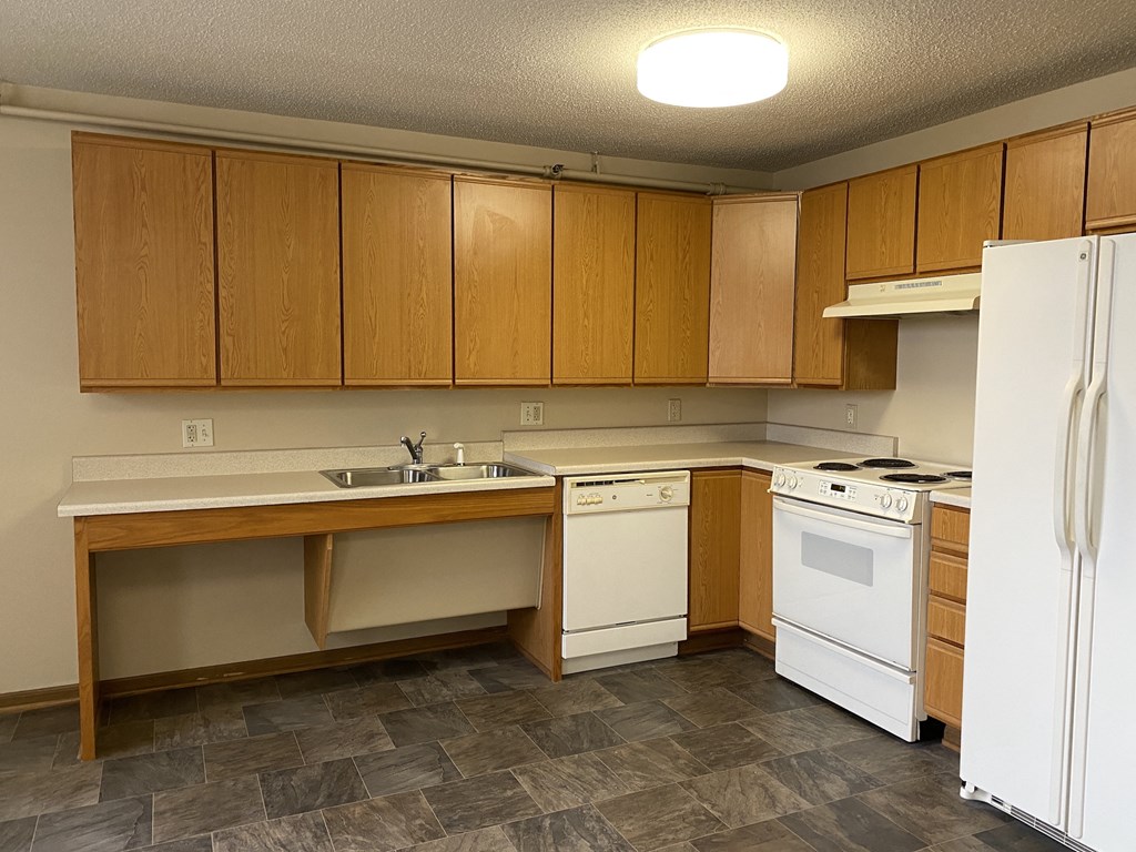 an empty kitchen with white appliances and wooden cabinets