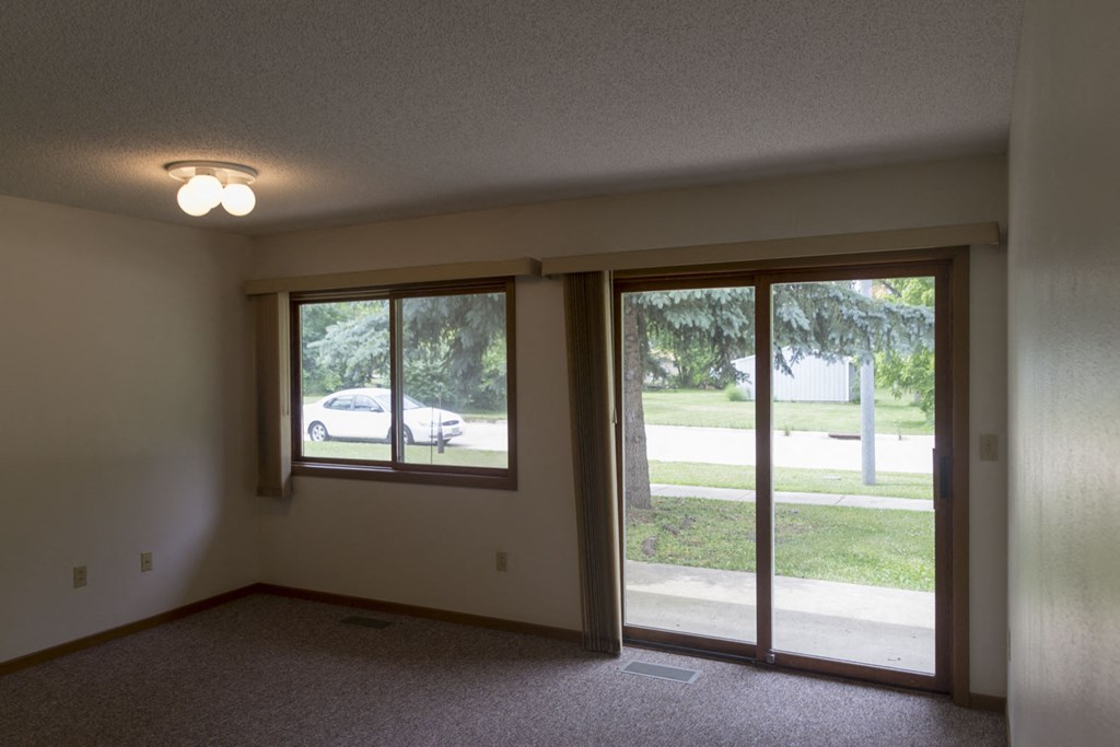 an empty living room with large windows and a white car outside