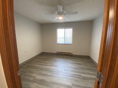 an empty living room with wooden floors and a ceiling fan