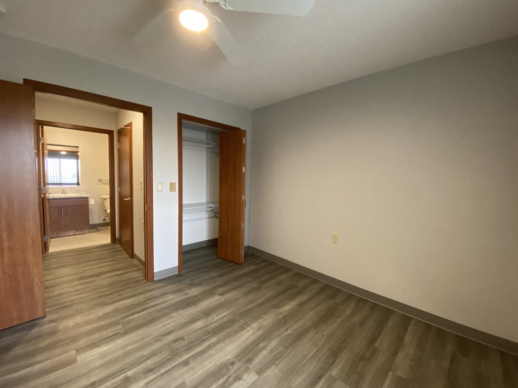 an empty living room with wooden floors and a door to a bathroom