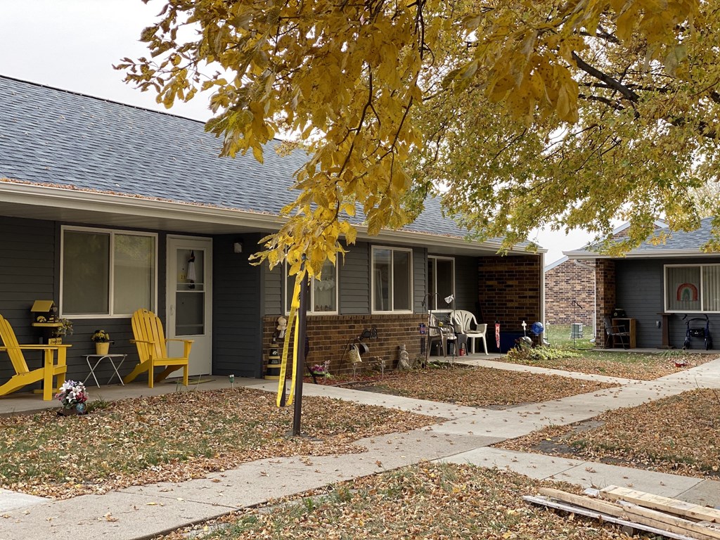 a yard in front of a house with yellow chairs