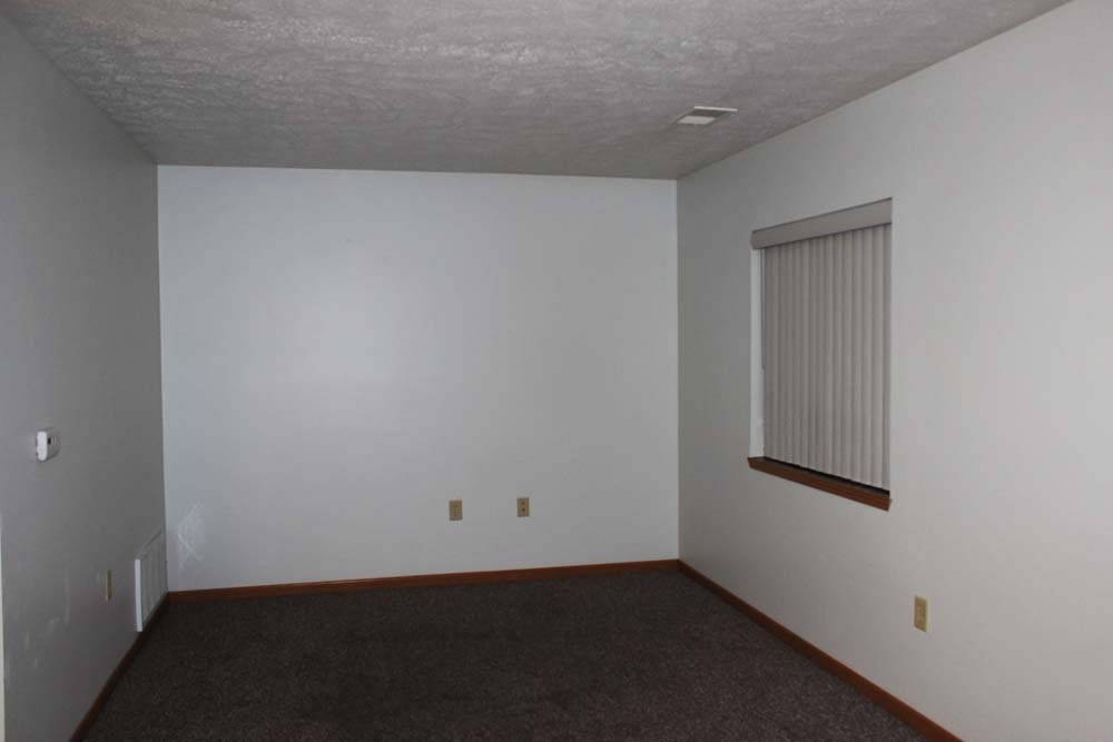 an empty room with a window and a carpet