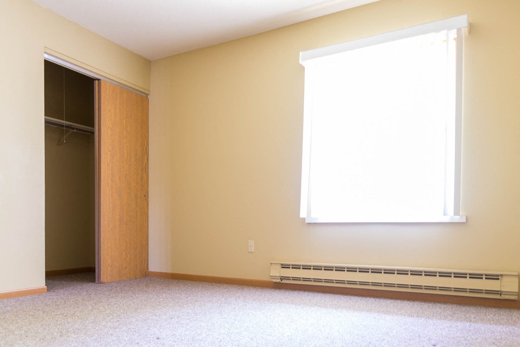 an empty room with a window and a closet