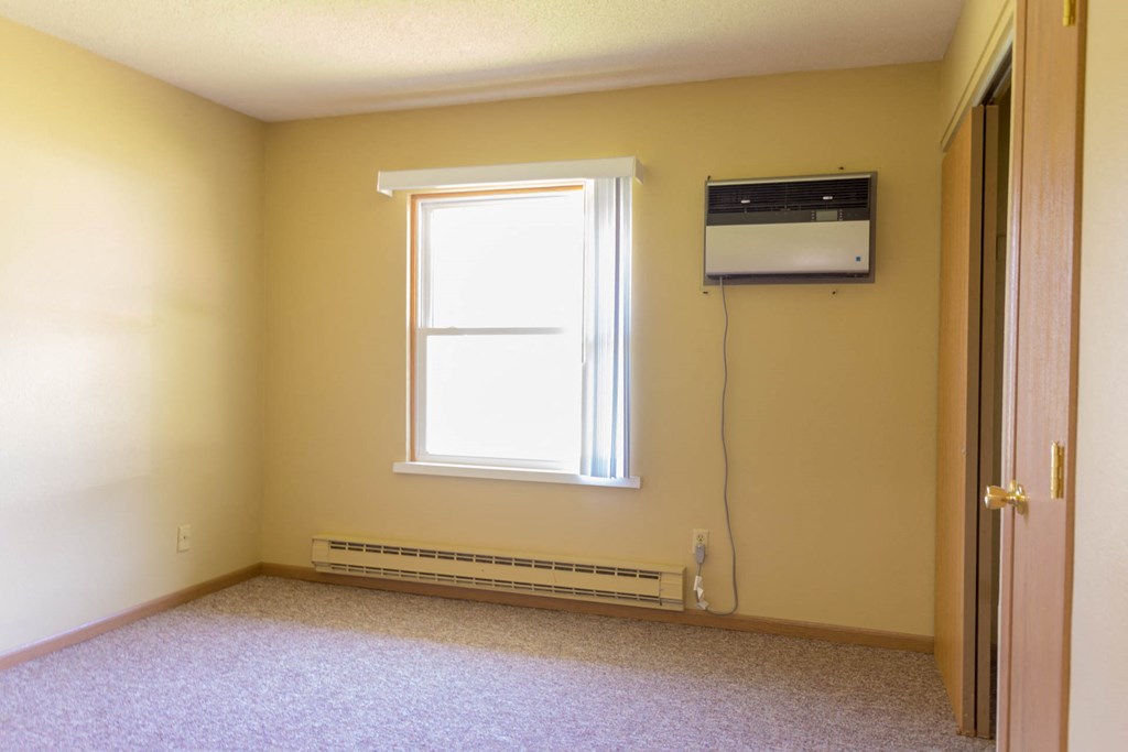 an empty room with a window and a air conditioner