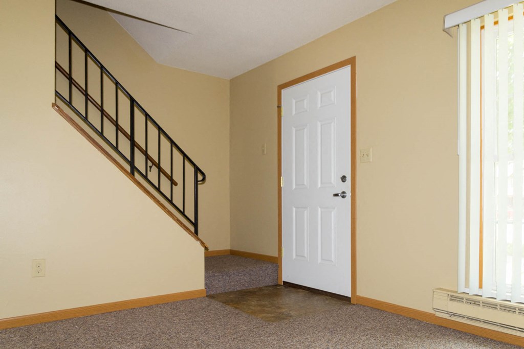 the entryway of a house with a white door and a staircase