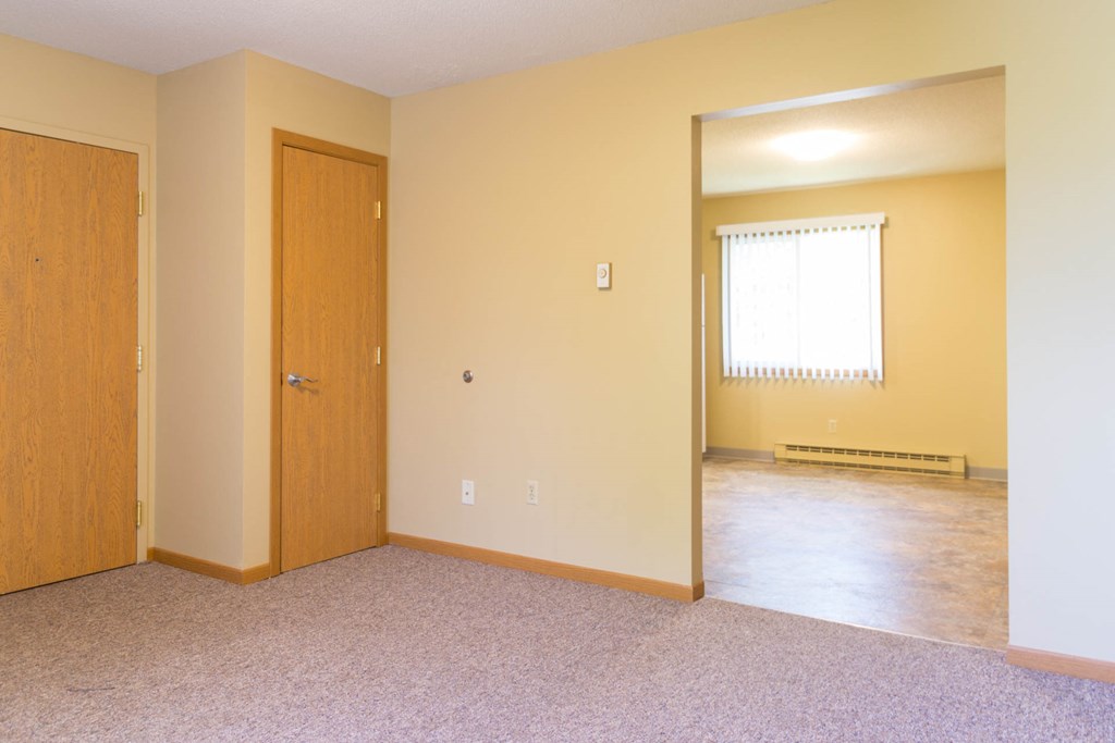 the living room and dining room of an empty house with a door