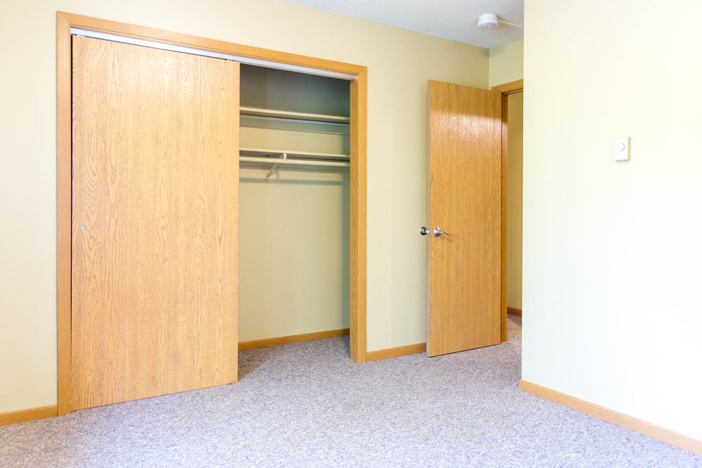 an empty bedroom with two closets and two doors