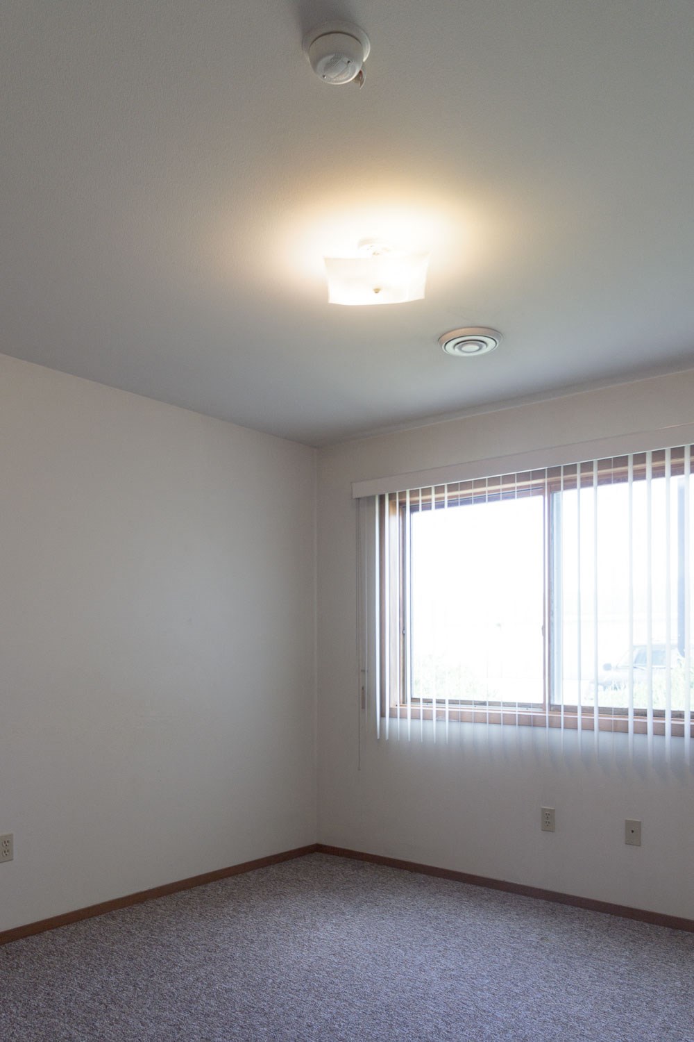 the living room of an empty apartment with a large window