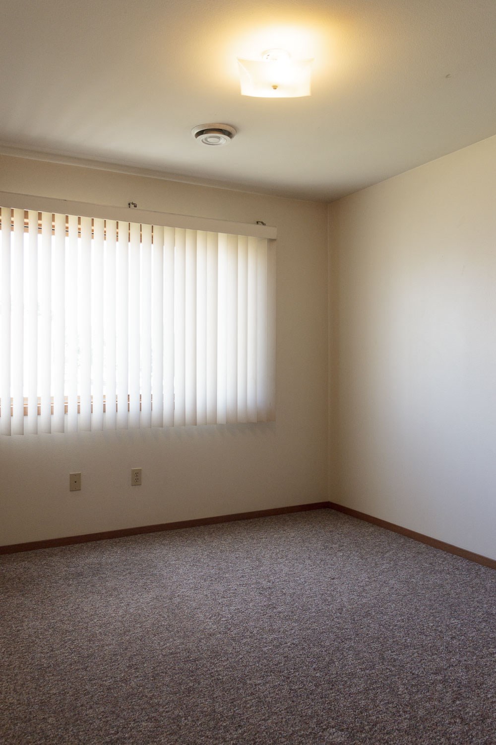 an empty room with white walls and window blinds
