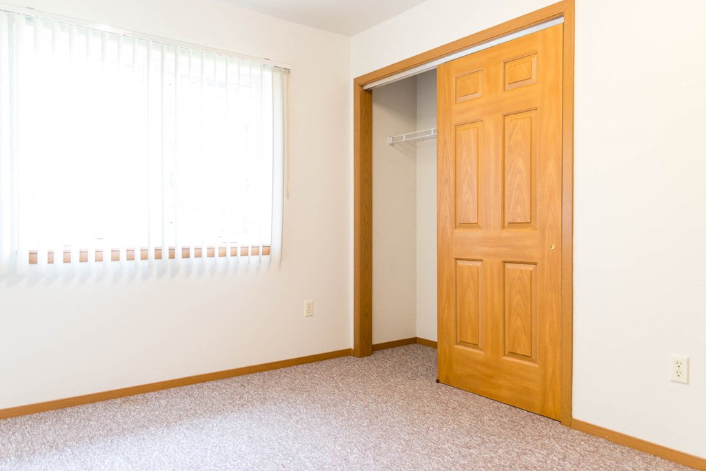 an empty bedroom with a closet and a door open