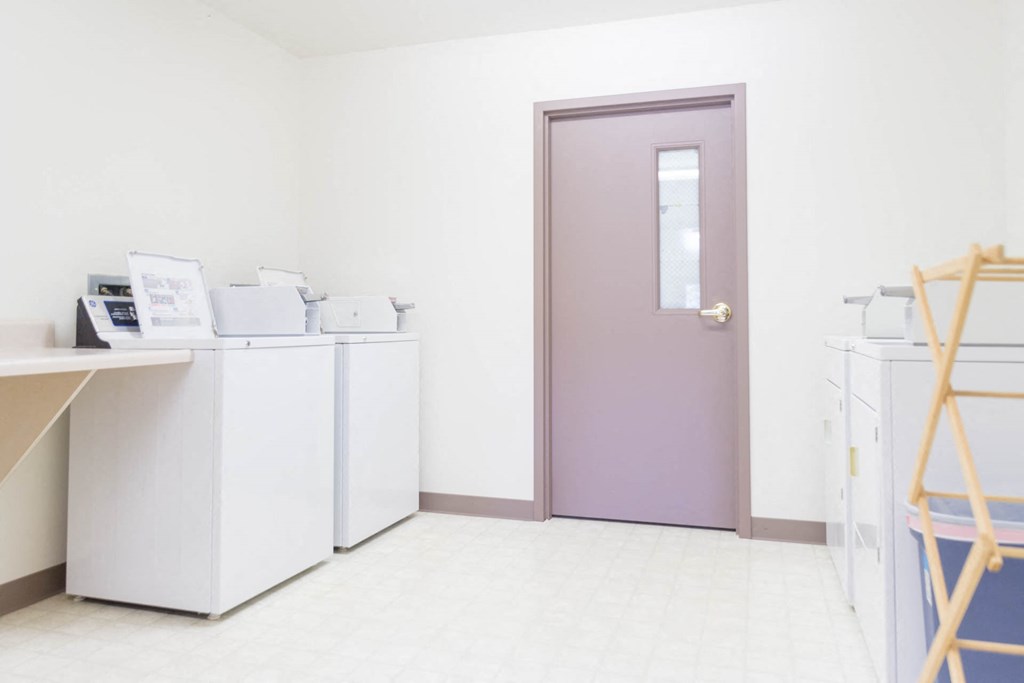 a laundry room with washes and dryers and a purple door