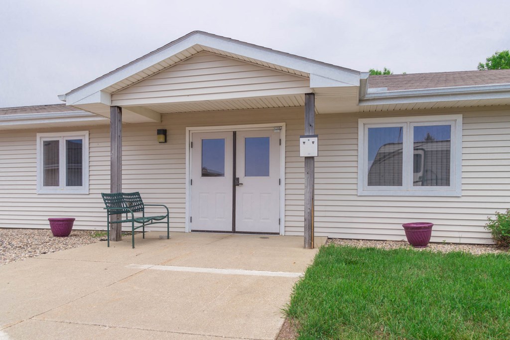 the front entrance of a white house with a patio and a bench