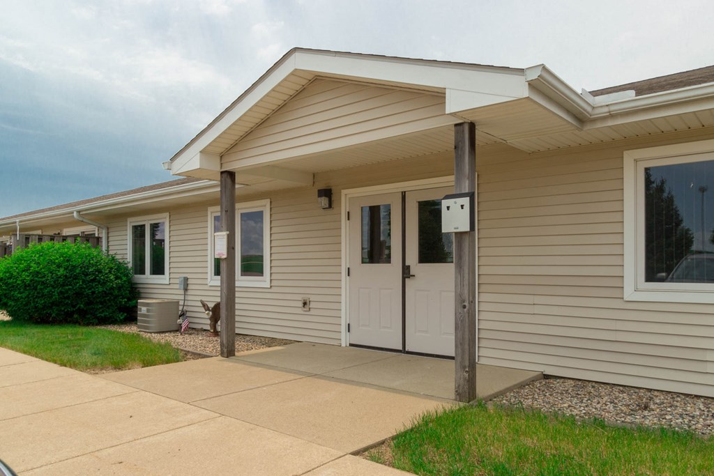 the front of a tan house with a white door and a sidewalk