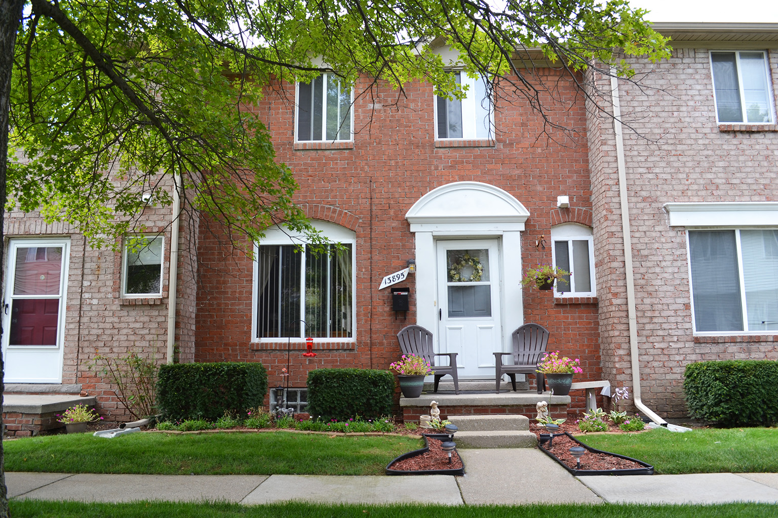 the front of a brick house with a porch and a white door