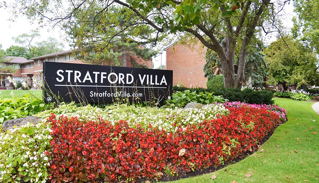 a sign in front of a garden of flowers