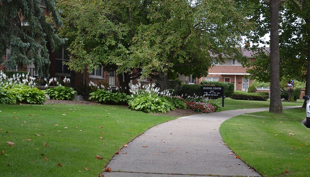 a sidewalk in front of a building with trees and flowers