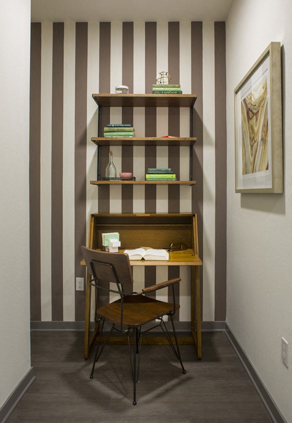 a desk with a chair in front of a shelf with books