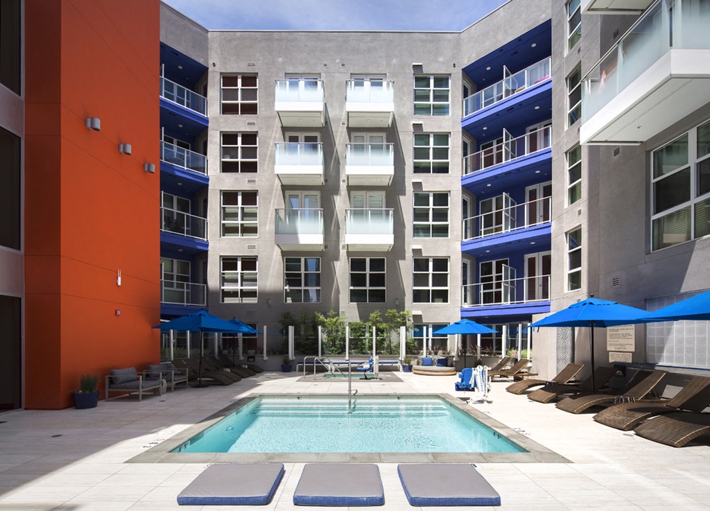 a swimming pool in front of a building with umbrellas
