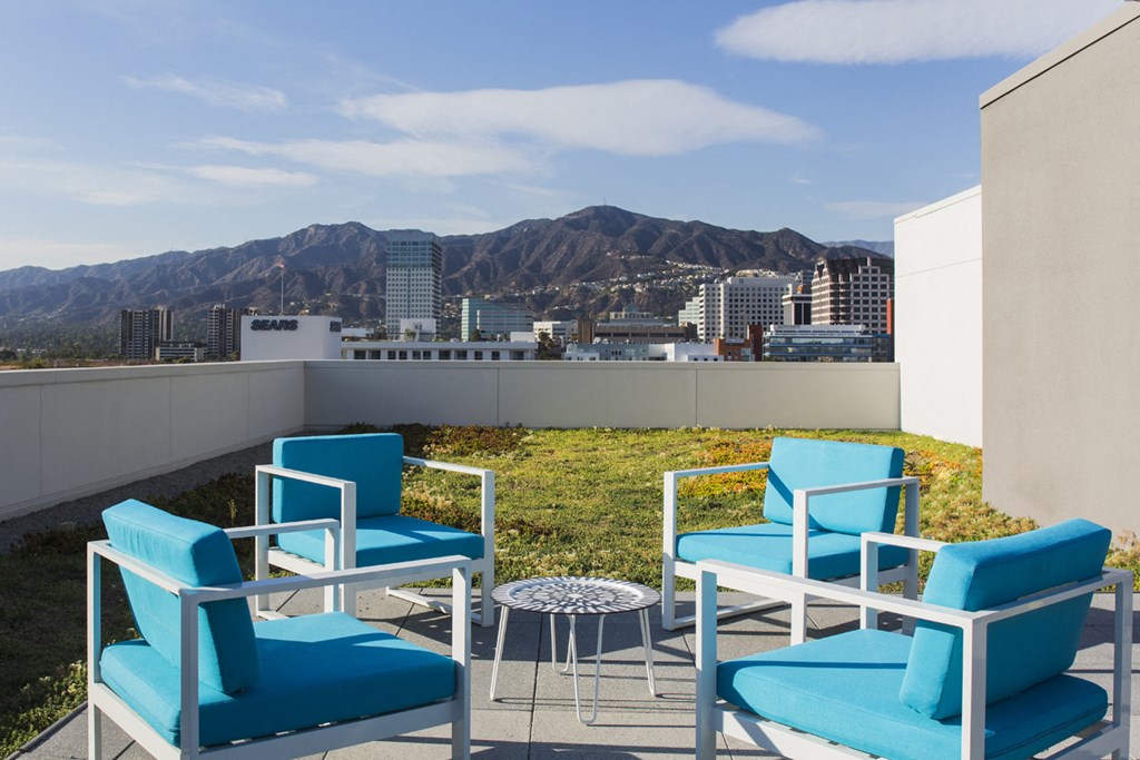 a patio with blue chairs and a view of the city