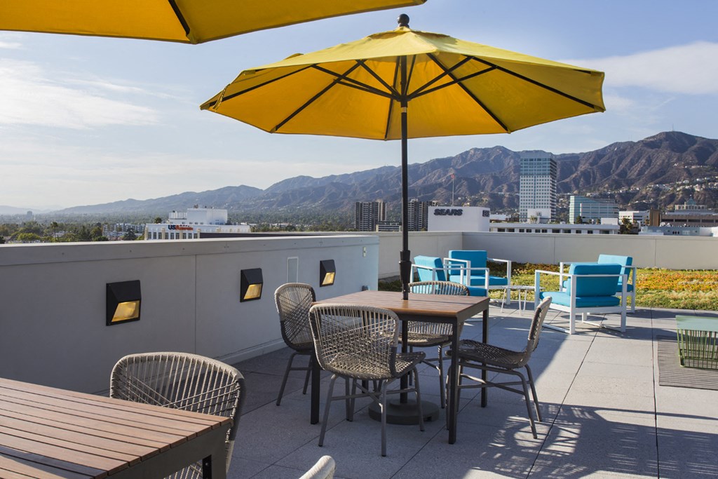 a rooftop patio with tables and chairs and a yellow umbrella