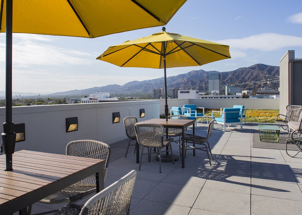 a rooftop patio with tables and chairs and umbrellas