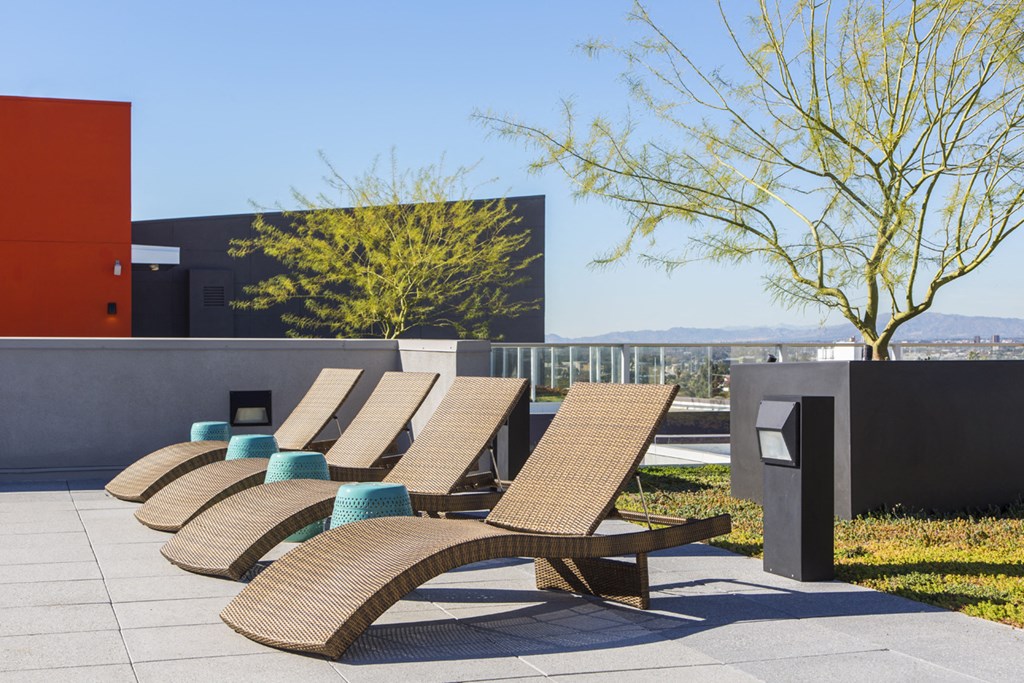 a row of wicker lounge chairs with blue cushions on a patio