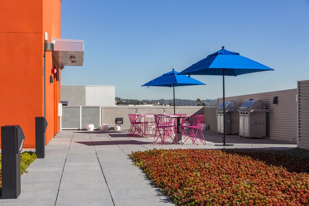 a patio with chairs and umbrellas on the roof of a building