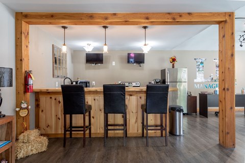 a kitchen with a bar with three chairs in front of it