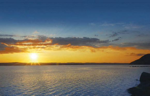 a sunset over the water with the sun shining over the ocean
