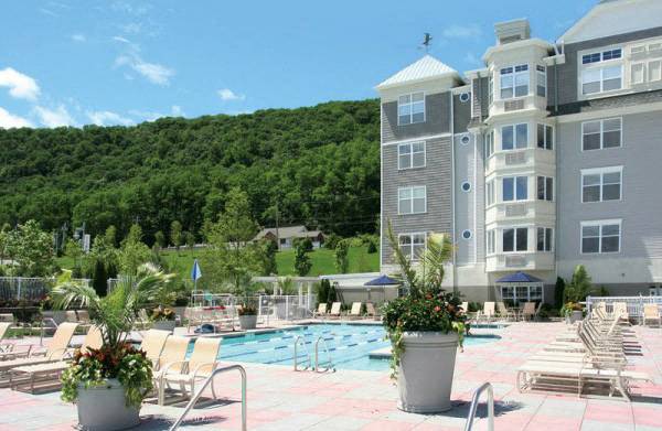 a swimming pool with chairs and potted plants in front of a building