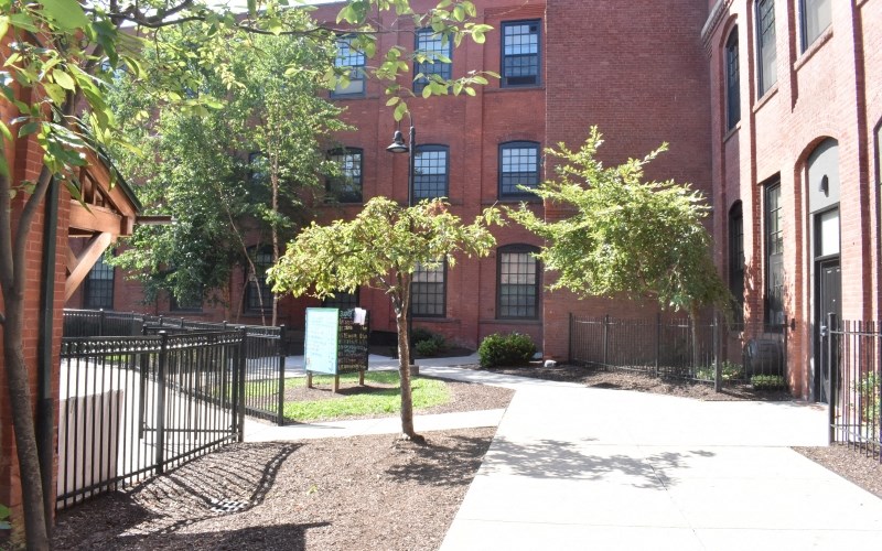 the courtyard of a brick building with trees and a sidewalk