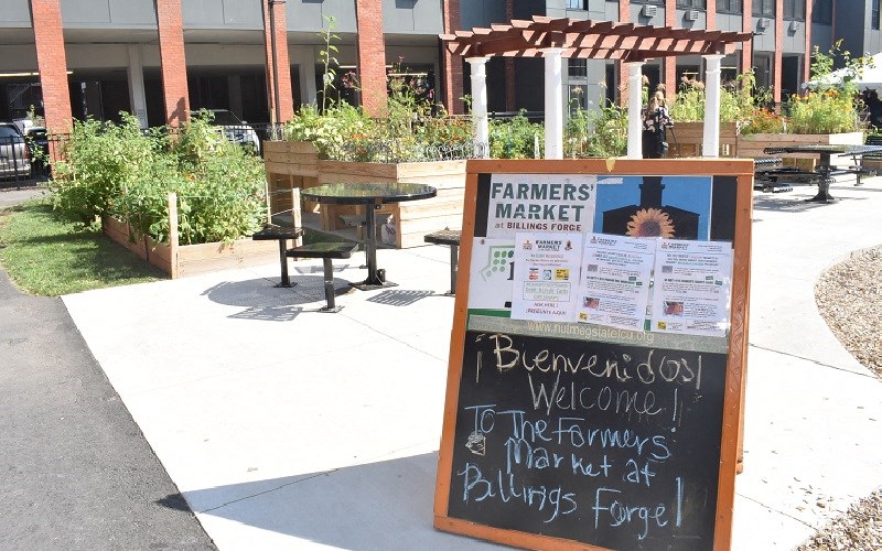 a sign outside of a farmers market in front of a building
