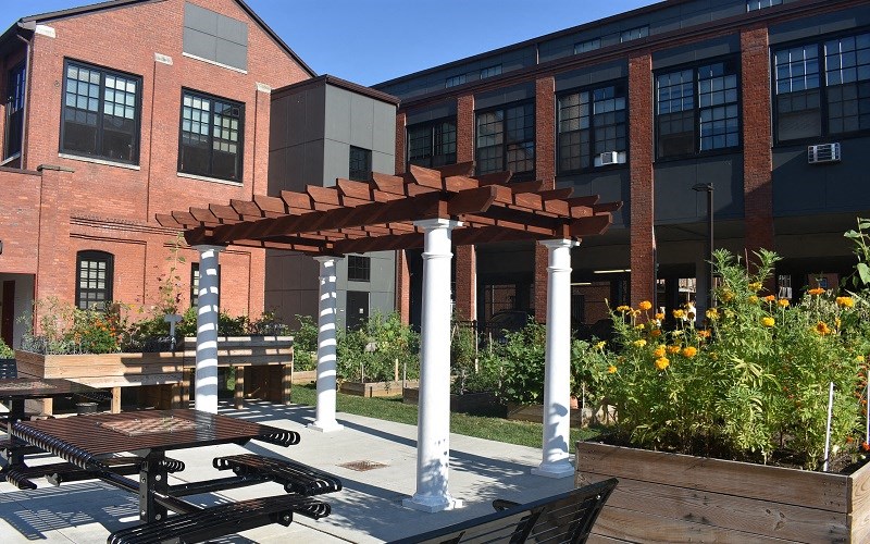 a patio with benches and a pergola in front of a building