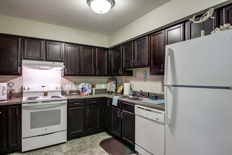 a kitchen with white appliances and dark cabinets