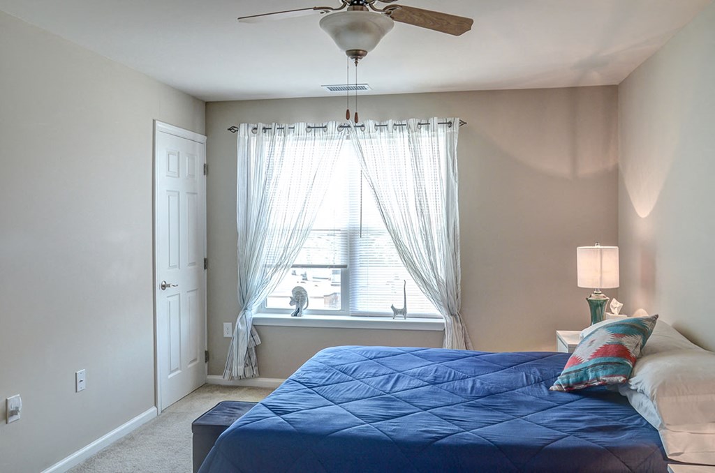 a bedroom with a bed and a window with a ceiling fan
