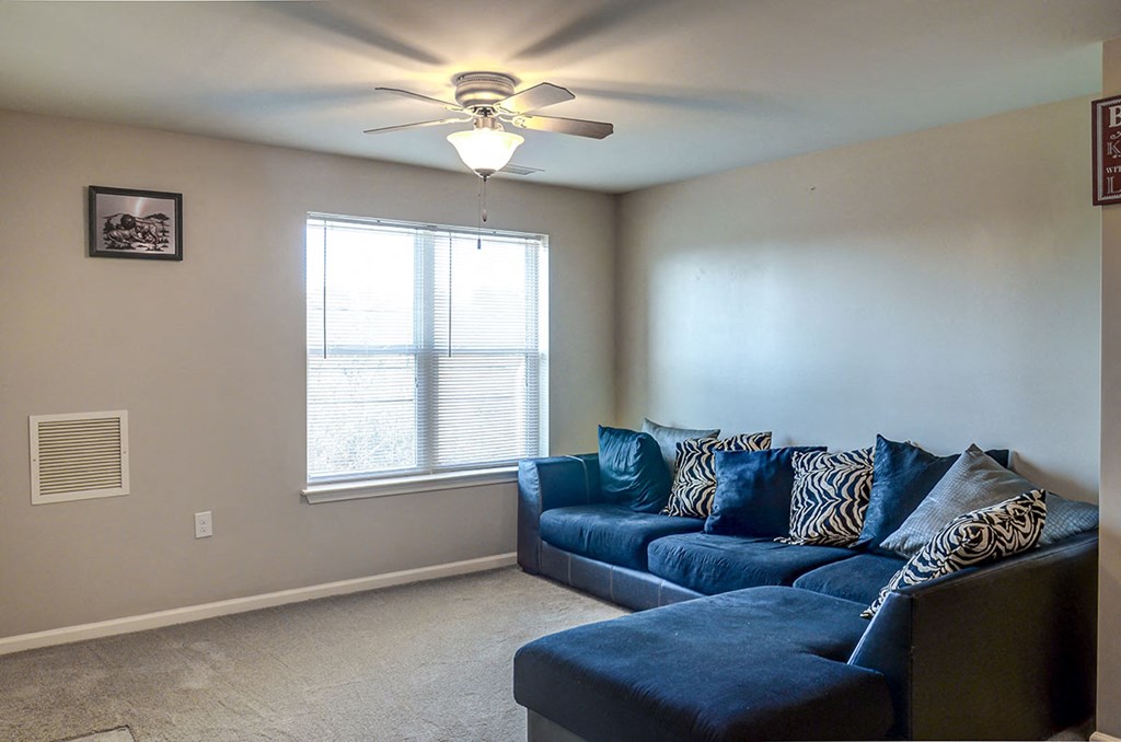 a living room with a blue couch and a ceiling fan