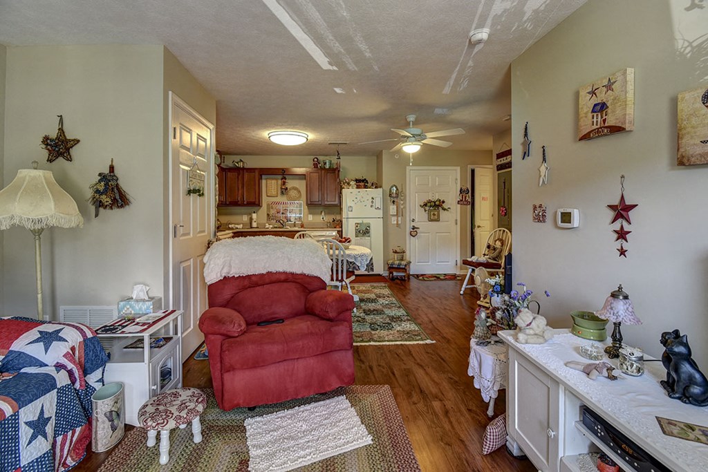 a living room and kitchen with a bed and a red chair