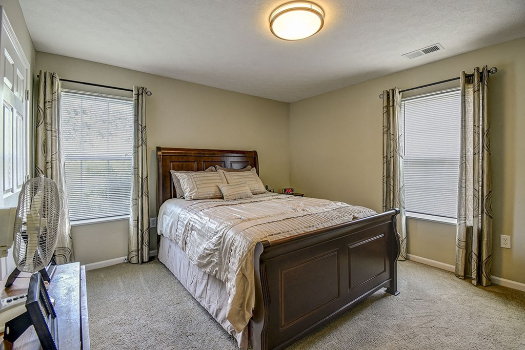 a bedroom with a bed and two windows