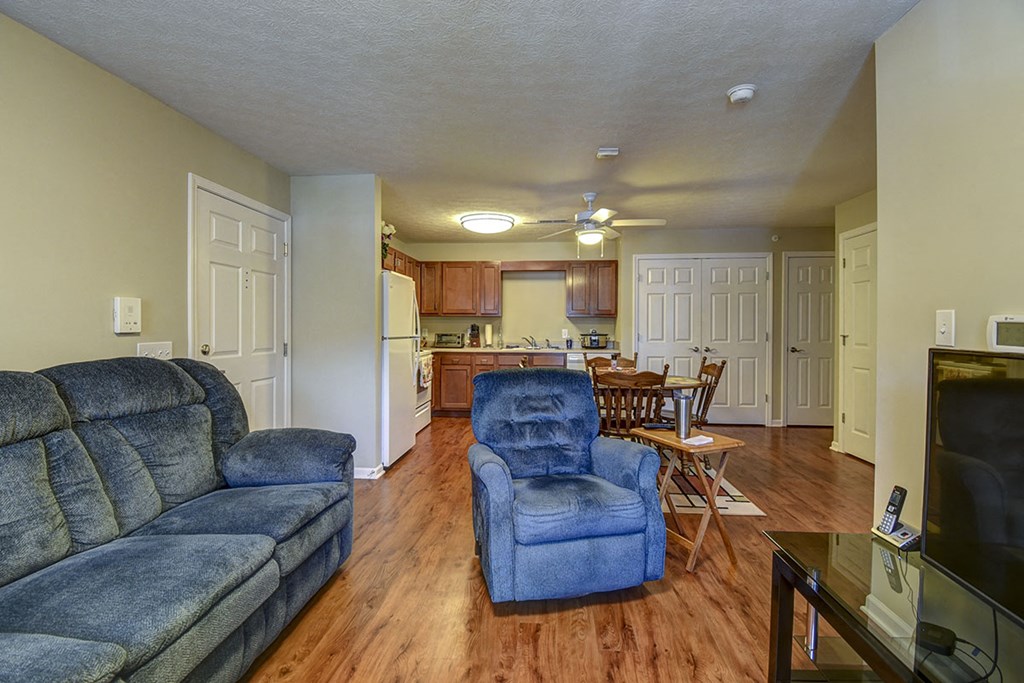 a living room and kitchen with a couch and chairs