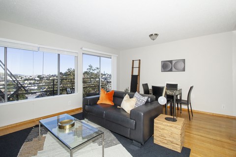 a living room with a couch and a glass coffee table and a dining room table