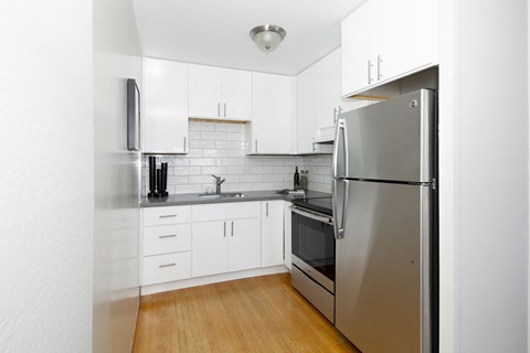a kitchen with white cabinets and a stainless steel refrigerator