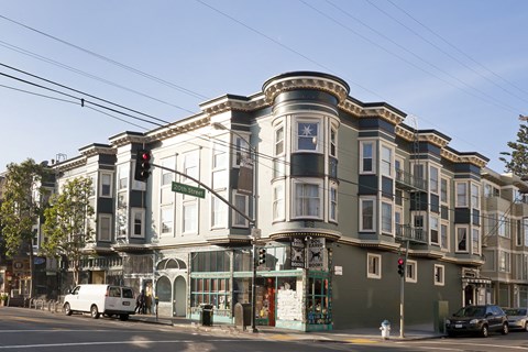 A street view of a building with a green awning and a white van parked in front.