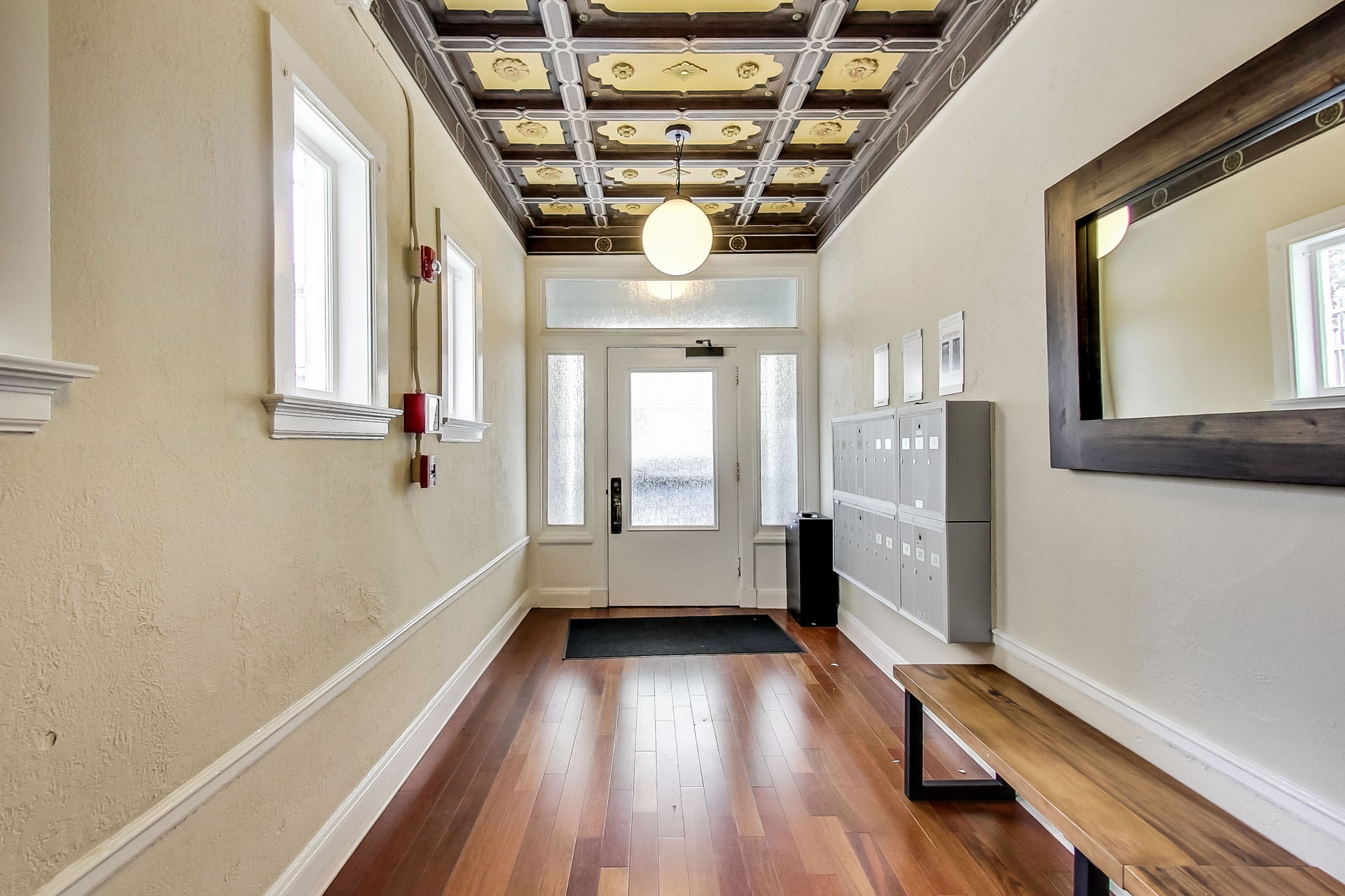 A hallway with a wooden floor and a ceiling with lights.